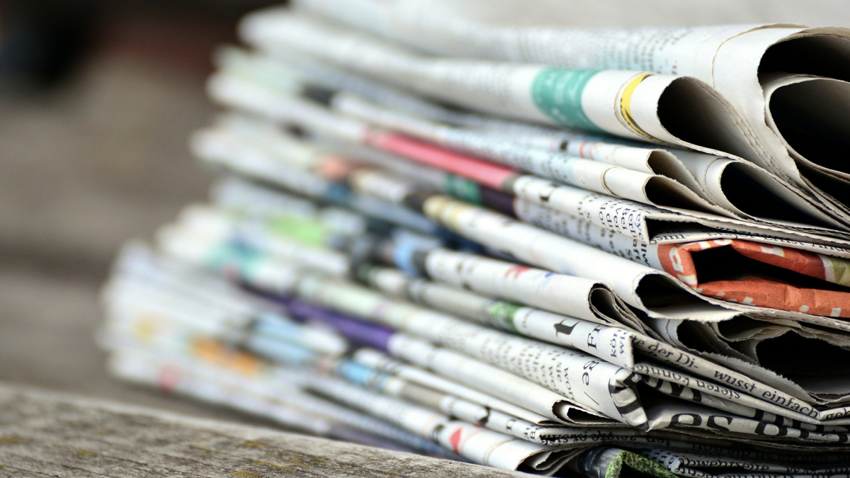 Newspapers stacked on a table.