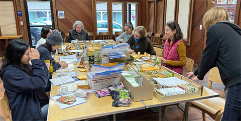 People seated around a table, preparing packets of seeds for the seed library.